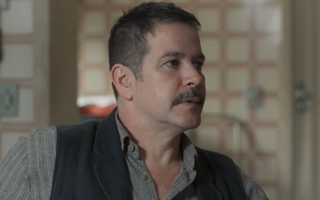 Murilo Benício caracterizado como Tenório em Pantanal: ator tem o cabelo bem aparado e ostenta um longo bigode. Ele veste uma camisa e um colete surrado e tem a expressão séria em cena de Pantanal