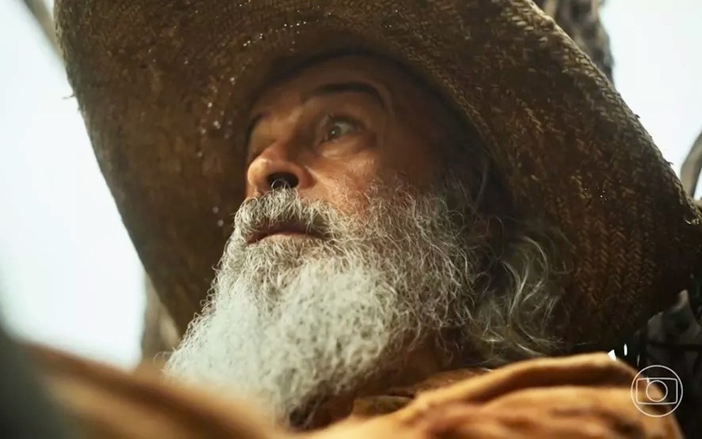 O ator Osmar Prado, caracterizado como Velho do Rio, usa chapéu e exibe um olhar assustado em cena de Pantanal, novela das nove da Globo