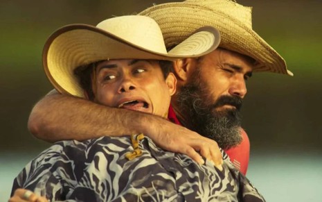 Alcides (Juliano Cazarré) abraça Zaquieu (Silvero Pereira) por trás em Pantanal; o último tem a expressão aterrorizada