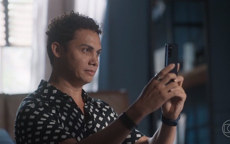 Zaquieu, personagem de Silvero Pereira, olha para celular em gravação de cena da novela Pantanal, da Globo