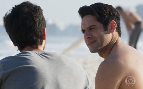 João Baldasserini grava na praia olhando para Bernardo Marinho, de costas na foto, como Agnaldo e Wanderley de Pega Pega