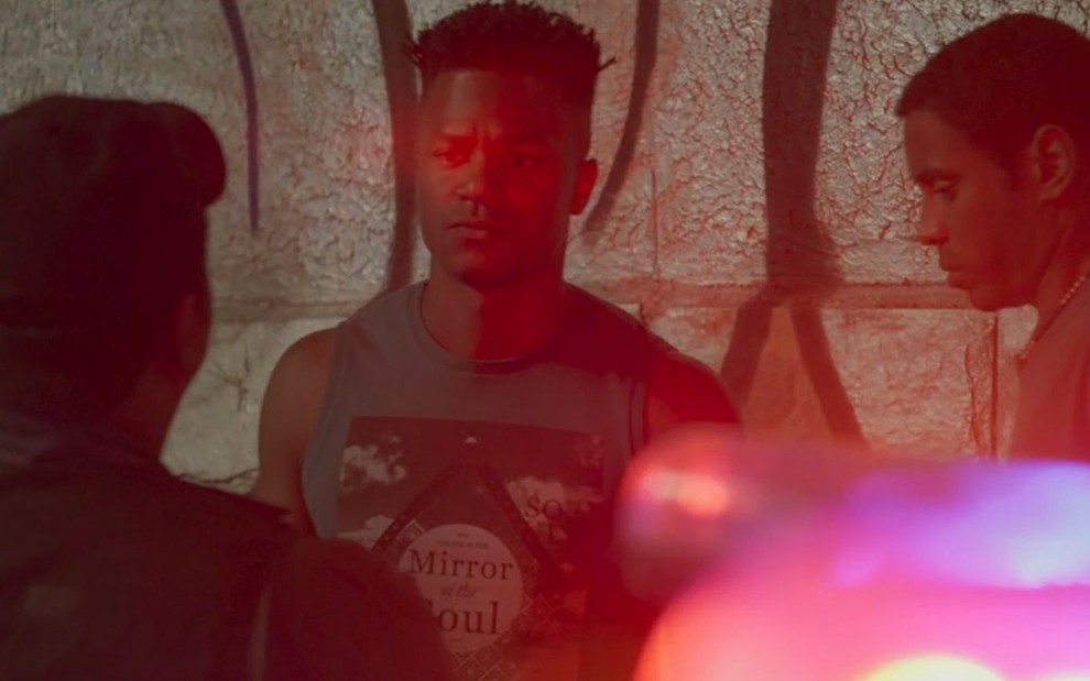 Dom (David Junior) é abordado por policial, Dilson (Ícaro Silva) está ao seu lado de cabeça baixa em cena de Pega Pega