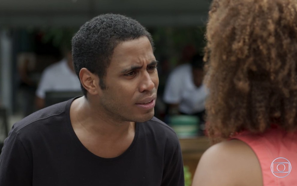 Ícaro Silva grava com camiseta preta e expressão de raiva olhando para Jennifer Nascimento, de costas, como Dilson e Tânia