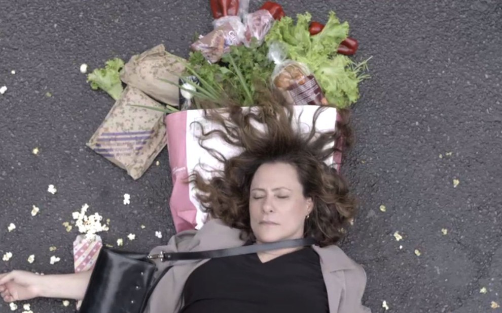 Arlete (Elizabeth Savala)  está caída no asfalto após atropelamento; há pipocas, legumes e bolsas jogadas em cena de Pega Pega