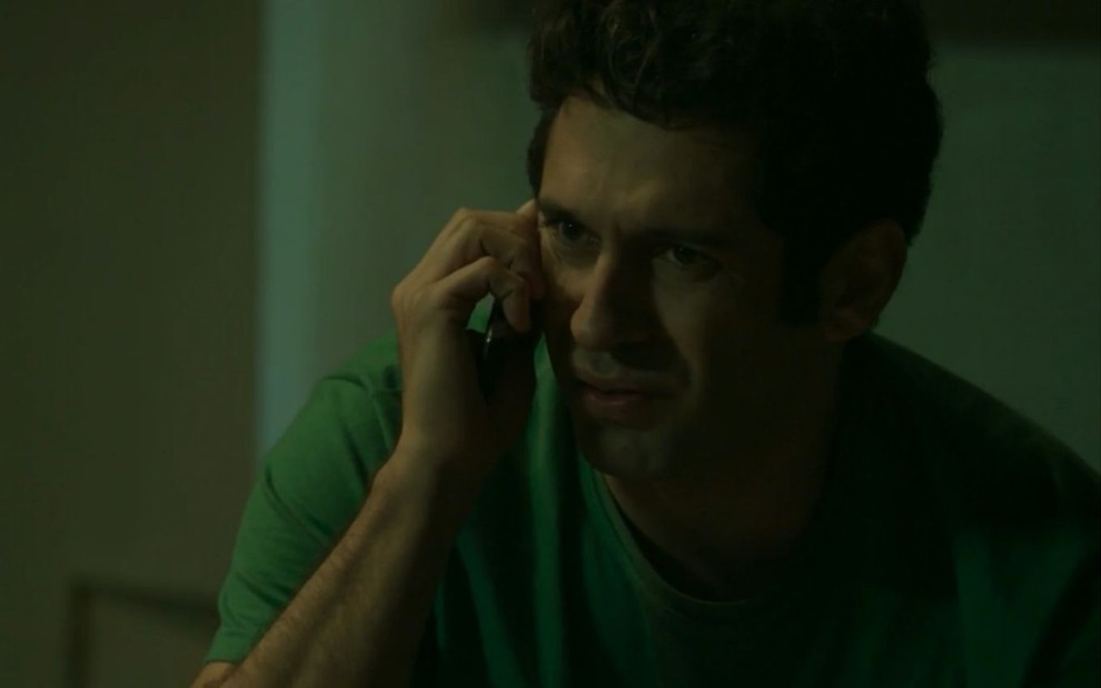 João Baldasserini grava cena falando no celular com Marcelo Serrado, que não aparece na imagem, com expressão confusa, como Agnaldo