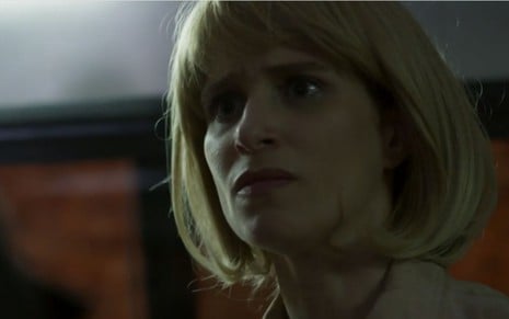 Mônica (Julia Lund) está em pé dentro de ônibus e disfarçada com peruca loira, lisa e de cabelo curto em cena de Pega Pega