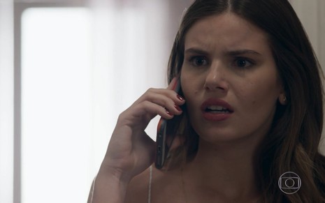 Camila Queiroz grava com celular na orelha e expressão de horror como Luiza de Pega Pega, reprise da Globo