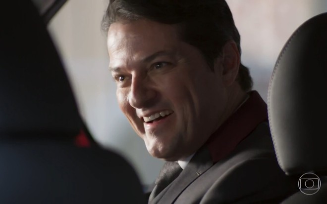 Marcelo Serrado grava vestindo terno, dentro de um carro e sorridente como Malagueta de Pega Pega
