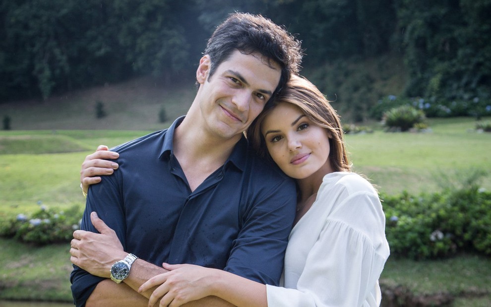 Mateus Solano é abraçado por Camila Queiroz perto de um lago durante gravação da novela Pega Pega, da Globo