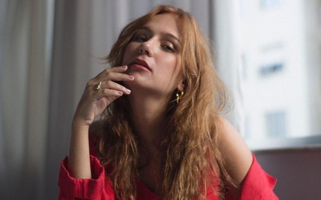 Carol Garcia em foto publicada no Instagram: com os cabelos soltos, atriz posa com a mão no queixo e usa blusa vermelha