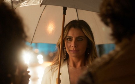 Paula (Giovanna Antonelli) está vestida de branco e segura guarda-chuva em cena de Quanto Mais Vida, Melhor!