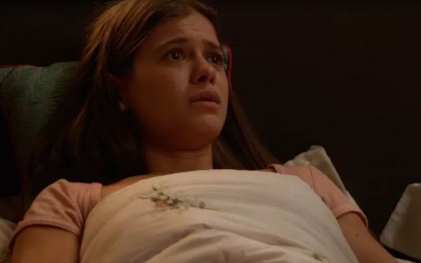 Bianca (Sara Vidal) está deitada em cama e chora em cena de Quanto Mais Vida, Melhor!, novela das sete da Globo