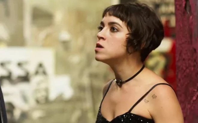 Cora (Valentina Bandeira) está parada em rua em cena de Quanto Mais Vida, Melhor!