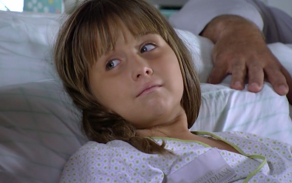 A atriz Jesuela Moro, em uma cama de hospital, em cena como Júlia de A Vida da Gente