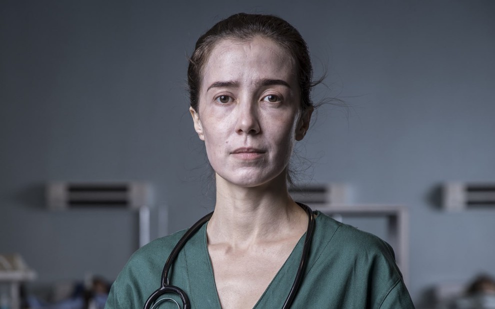 Marjorie Estiano posa com expressão de cansaço em cenário de ambiente hospitalar da série Sob Pressão, da Globo