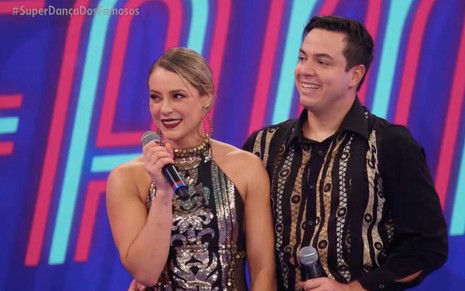 A atriz Paolla Oliveira à esquerda segura um microfone ao lado do professor Leandro Azevedo na Super Dança dos Famosos