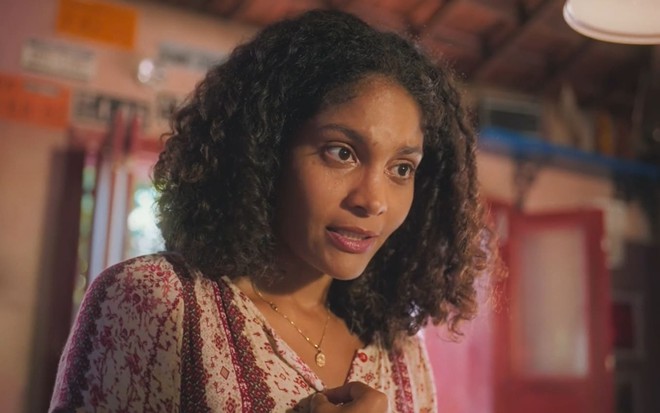Barbara Reis caracterizada como Aline; ela tem o semblante sério e usa uma roupa verde em cena de Terra e Paixão
