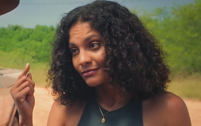 Barbara Reis caracterizada como Aline; ela usa uma camiseta verde e tem o semblante abalado em cena de Terra e Paixão
