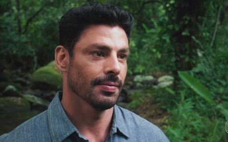 O ator Cauã Reymond usa camisa azul e está sério durante gravação de cena da novela Terra e Paixão
