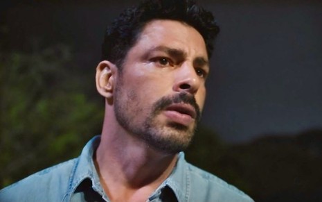 O ator Cauã Reymond está em close, com expressão séria, em cena da novela Terra e Paixão como o mocinho Caio