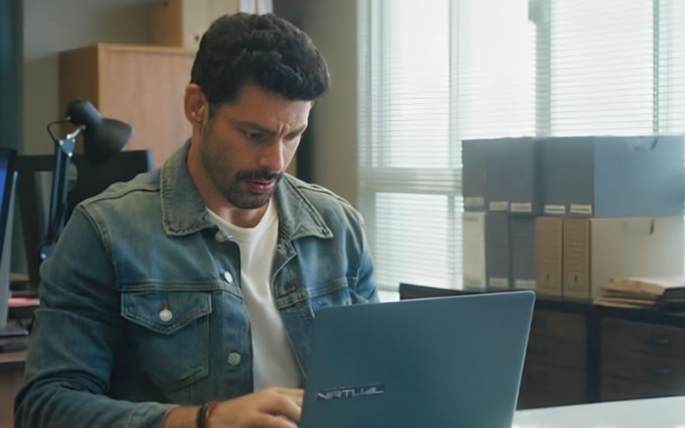 O ator Cauã Reymond como Caio na frente de um computador em cena de Terra e Paixão