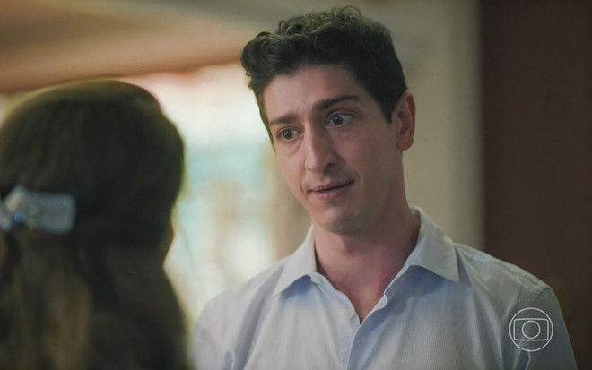 O ator Johnny Massaro está diante de Gloria Pires (de costas e cortada na imagem) em cena da novela Terra e Paixão