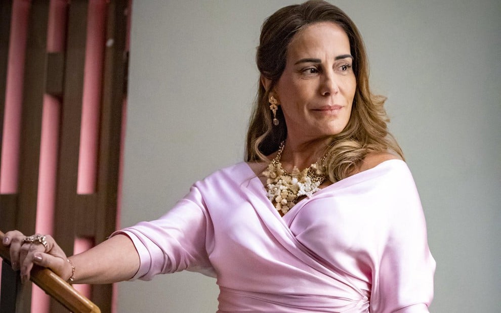 Gloria Pires usa blusa rosa e penteado lateral caracterizada como Irene da novela Terra e Paixão, da Globo