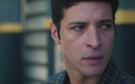 Leandro Lima caracterizado como Marino; ator usa uma camiseta xadrez e parece furioso em cena da novela