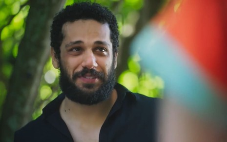 Amaury Lorenzo caracterizado como Ramiro; ele usa uma camisa preta e dá um leve sorriso em cena de Terra e Paixão. Diego Martins, o Kelvin, está de costas para a câmera e encara o colega.