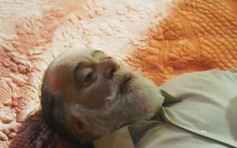 O ator Tony Ramos caracterizado como Antônio La Selva deitado na cama de Cândida em cena de Terra e Paixão