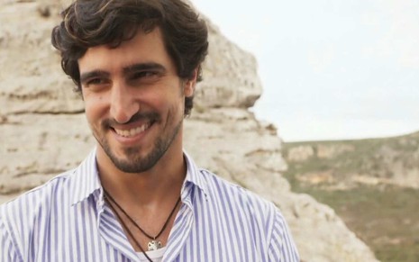 Ator Renato Góes sorri e olha para frente em cena de Mar do Sertão