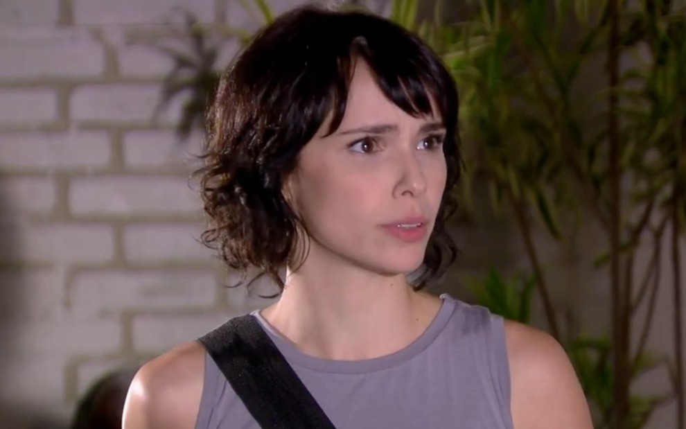 Débora Falabella em cena de Ti Ti Ti: atriz está caracterizada como Isabel e usa regata cinza, bolsa preta no ombro e cabelo curto repicado com franja