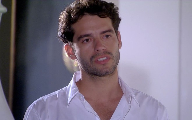 Guilherme Winter em cena de Ti Ti Ti: caracterizado com Renato, ator olha para fora com expressão de seriedade