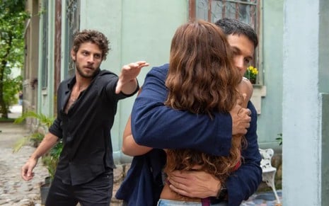 Romulo Estrela, o Oto, abraça Lucy Alves, a Brisa, em primeiro plano; ao fundo, é possível ver Chay Suede, com a expressão furiosa, avançando para puxar o outro homem pelo ombro