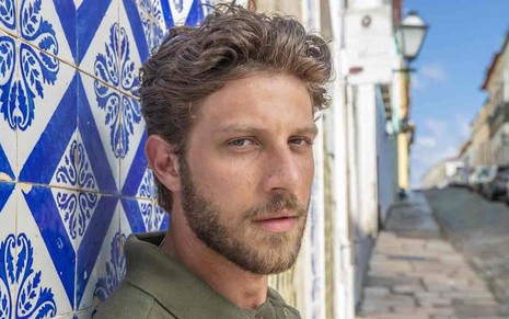 O ator Chay Suede olha para o lado em imagem feita em rua do Maranhão para a novela Travessia, da Globo