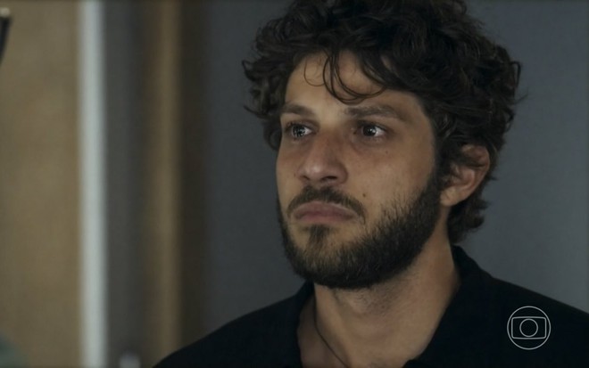 O ator Chay Suede está com os olhos lacrimejando em cena da novela Travessia como seu personagem Ari