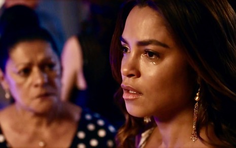 Luci Pereira olha para Lucy Alves, que está em close e com uma lágrima escorrendo do rosto, em cena de Travessia