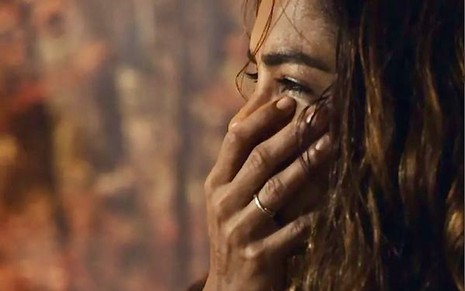 A atriz Lucy Alves está com a mão sobre o rosto em cena de choro de Brisa na novela Travessia