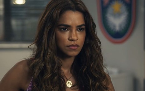 Lucy Alves caracterizada como Brisa; atriz usa um cropped florido e tem a expressão transtornada em cena de Travessia