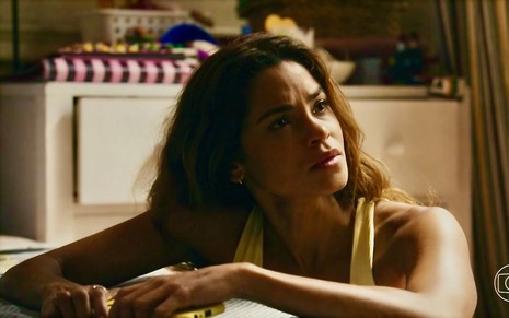 A atriz Lucy Alves usa regata amarela e olha para o lado em cena de Travessia em que está caracterizada como Brisa