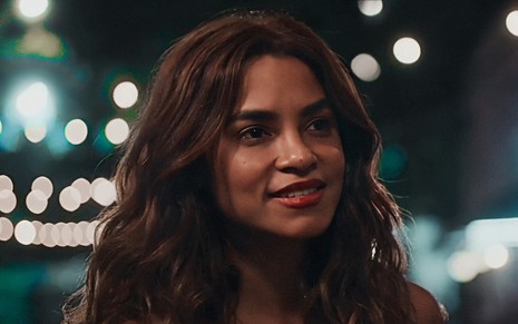 A atriz Lucy Alves está sorrindo em cena noturna da novela Travessia como a mocinha Brisa
