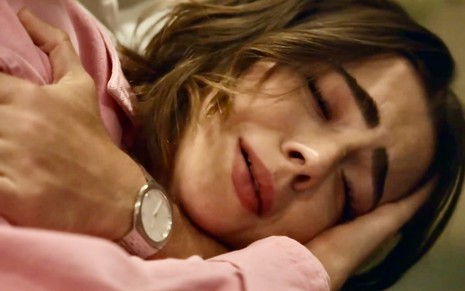 A atriz Jade Picon usa blusa de manga rosa e está encolhida no colo de alguém chorando em cena de Travessia, novela da Globo
