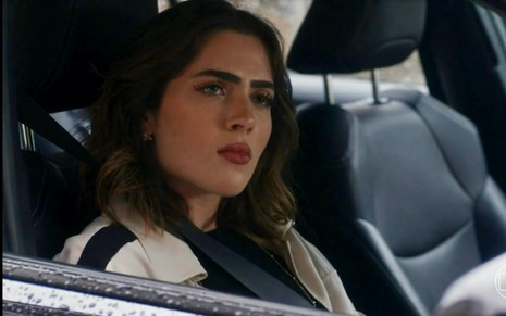 A atriz Jade Picon está com expressão de desagrado em cena de Travessia na qual está sentada em um automóvel como Chiara