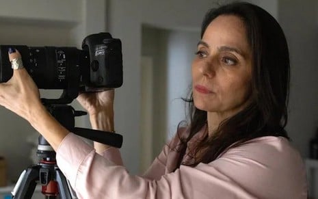A atriz Claudia Mauro está em cena de Travessia ao lado de uma câmera em um tripe como a personagem Pilar