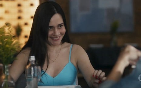 Em cena de Travessia, Alessandra Negrini está sorrindo, falando com alguém