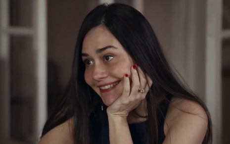 Alessandra Negrini caracterizada como Guida; ela usa uma blusa branca e dá um sorriso vingativo em cena de Travessia