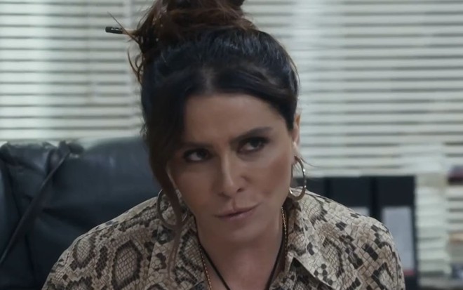 Giovanna Antonelli tem os cabelos presos em um coque e dá um meio sorriso em cena de Travessia