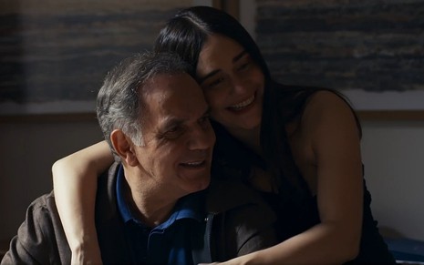 Guerra (Humberto Martins) e Guida (Alessandra Negrini) abraçados e sorrindo em cena de Travesseia
