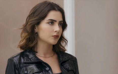 Chiara (Jade Picon) com expressão séria em cena de Travessia; ela veste jaqueta preta de couro