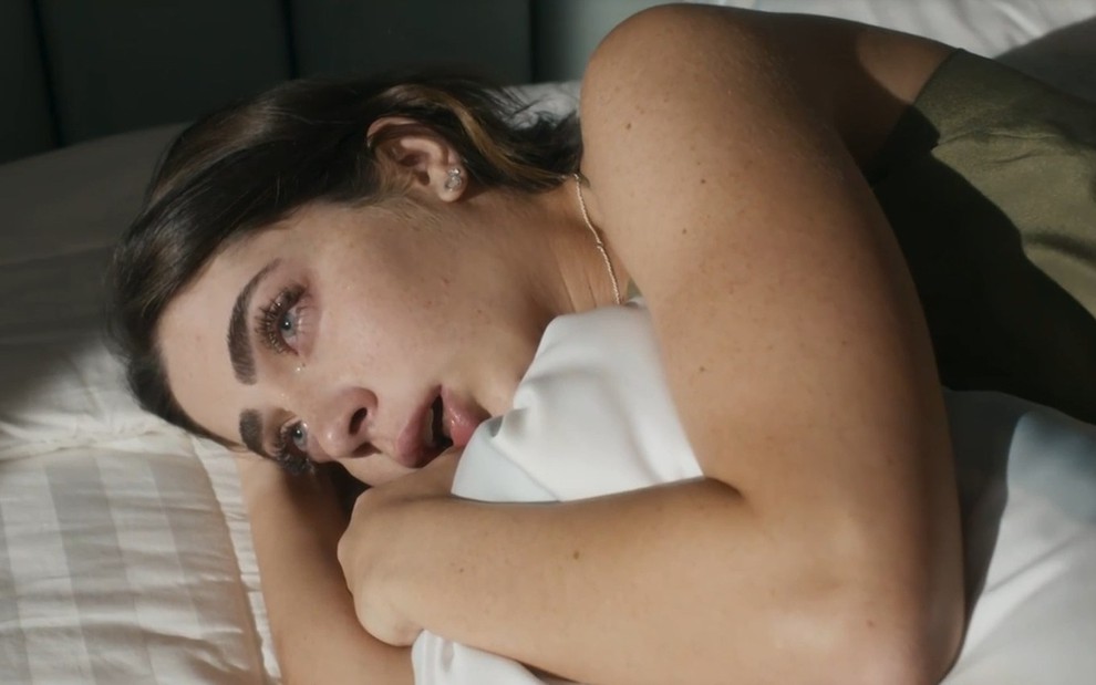 Jade Picon chora abraçada ao travesseiro em cena da novela Travessia (2022)